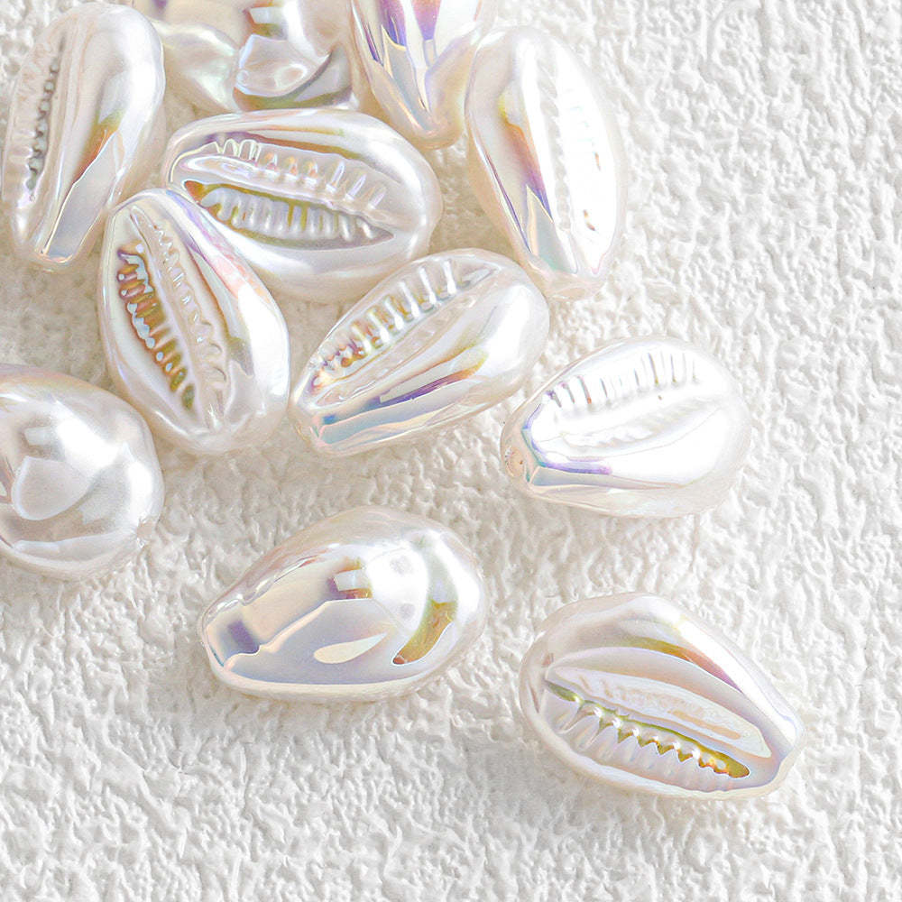 Cluster of teardrop-shaped iridescent shell beads with a pearly finish on white fabric