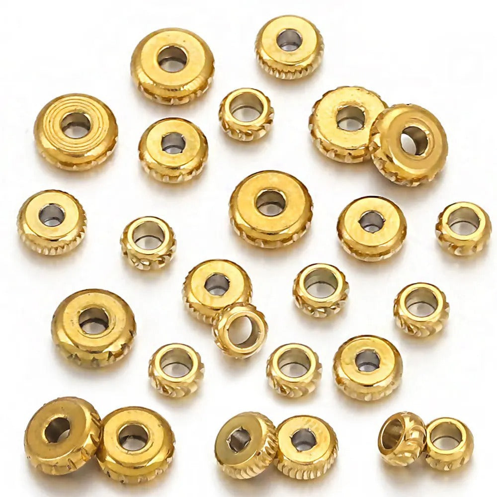 Gold-plated diamond-cut stainless steel abacus spacer beads scattered on a white background