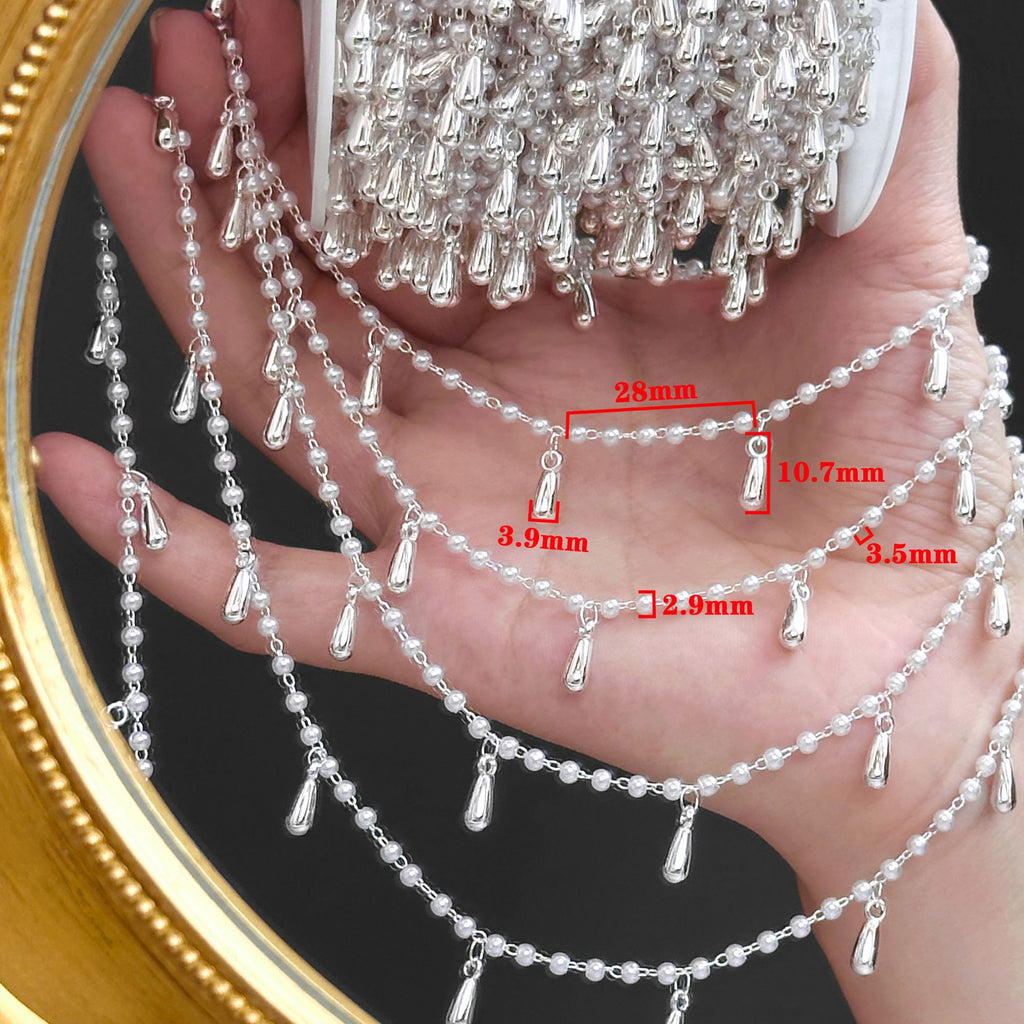 Hand holding silver beaded fringe chain with teardrop charms and red size labels