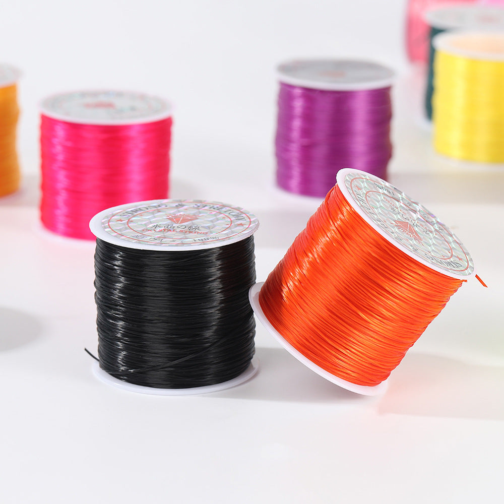 Black and bright orange spools of flat elastic beading cord with pink, purple and yellow spools blurred behind