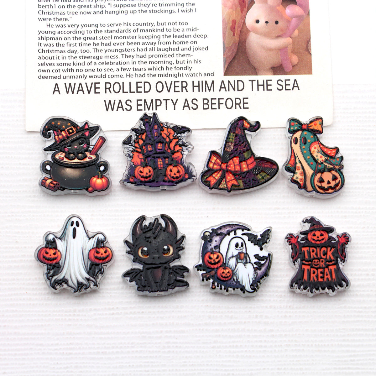Eight Halloween acrylic beads with ghost, pumpkin, witch hat, haunted house, and cat designs on white