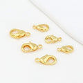 Gold teardrop lobster clasps on a white background