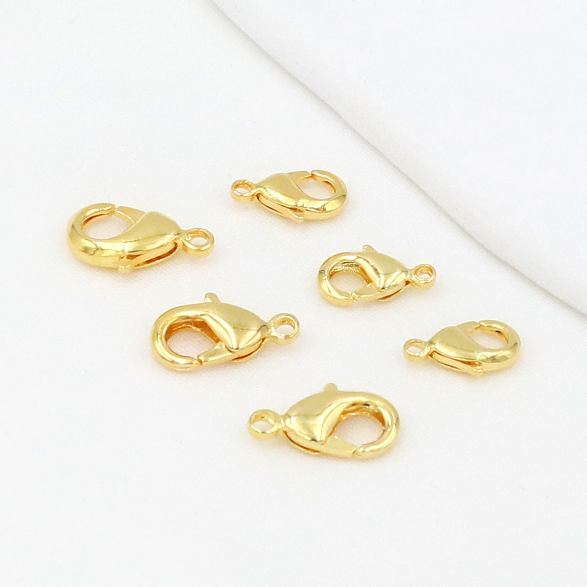 Gold teardrop lobster clasps on a white background