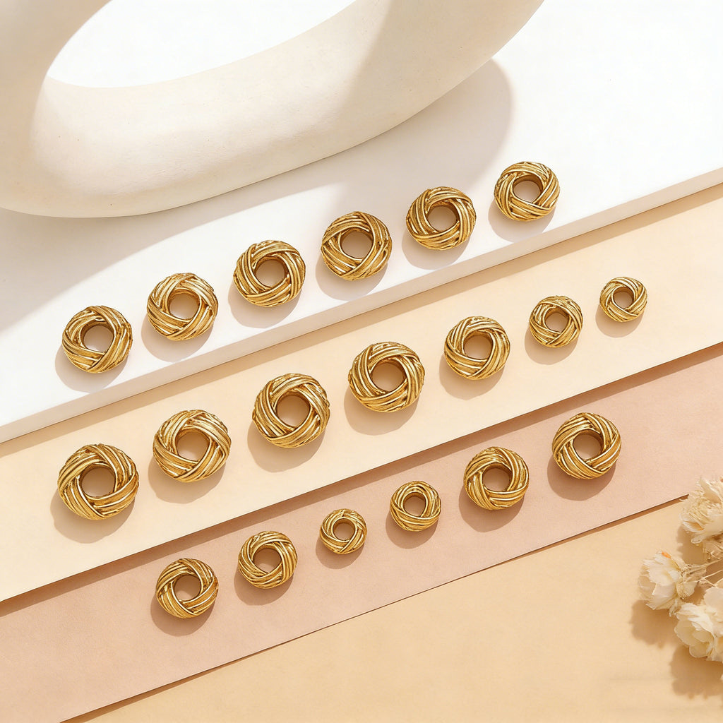 Gold-tone twisted bird's nest spacer beads arranged in rows on paper strips