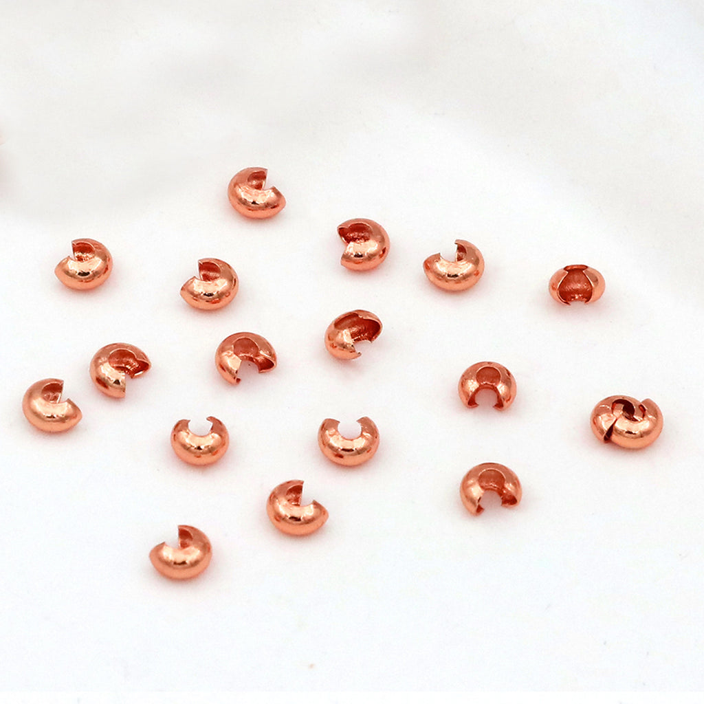 Small copper C-shaped crimp bead covers scattered on a plain white background