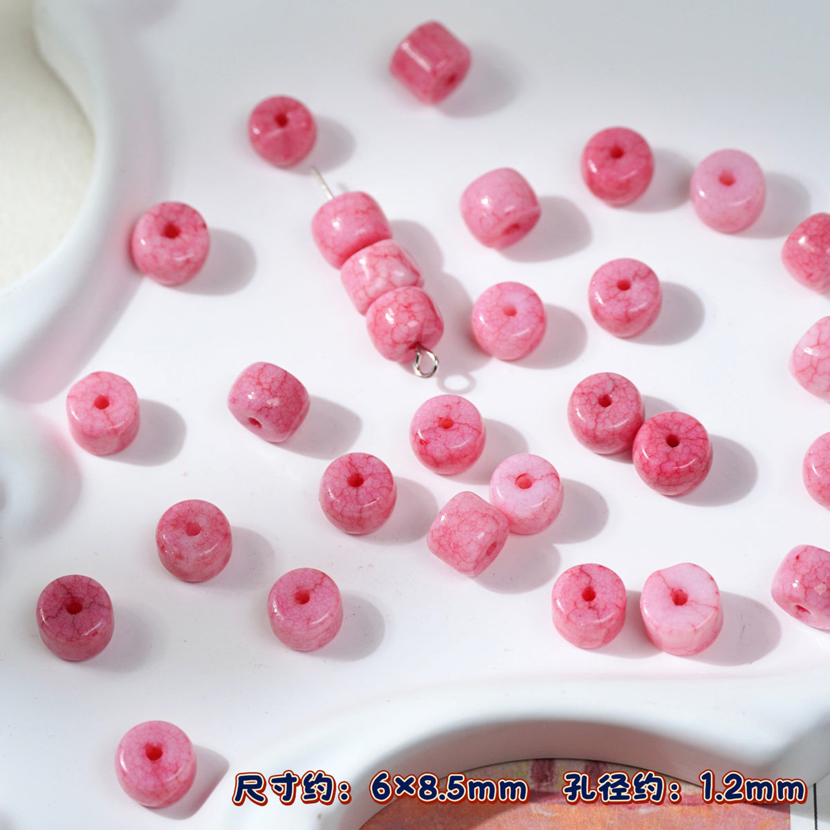 Pink marbled round porcelain beads on white, one bead string in center