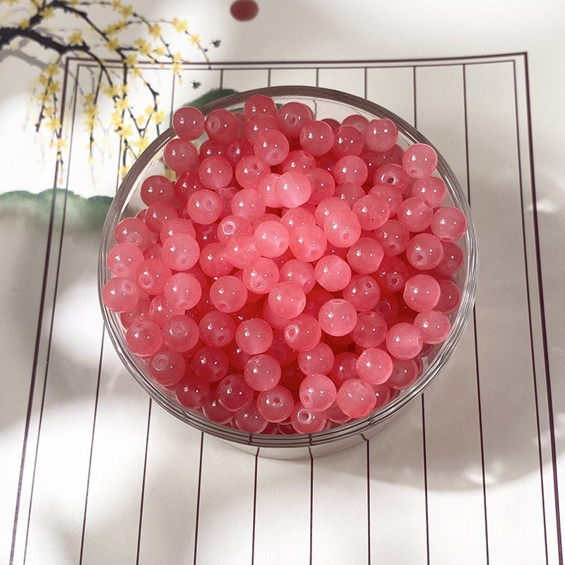 Translucent pink round beads in a clear glass bowl on decorative mat