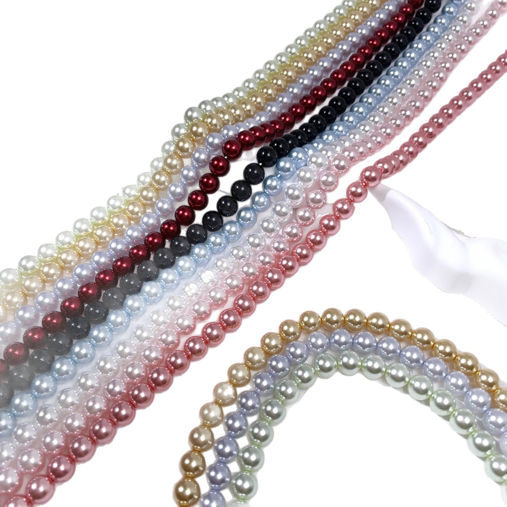Diagonal rows of glass pearl bead strands in gold, red, black, blue, pink, and cream on white