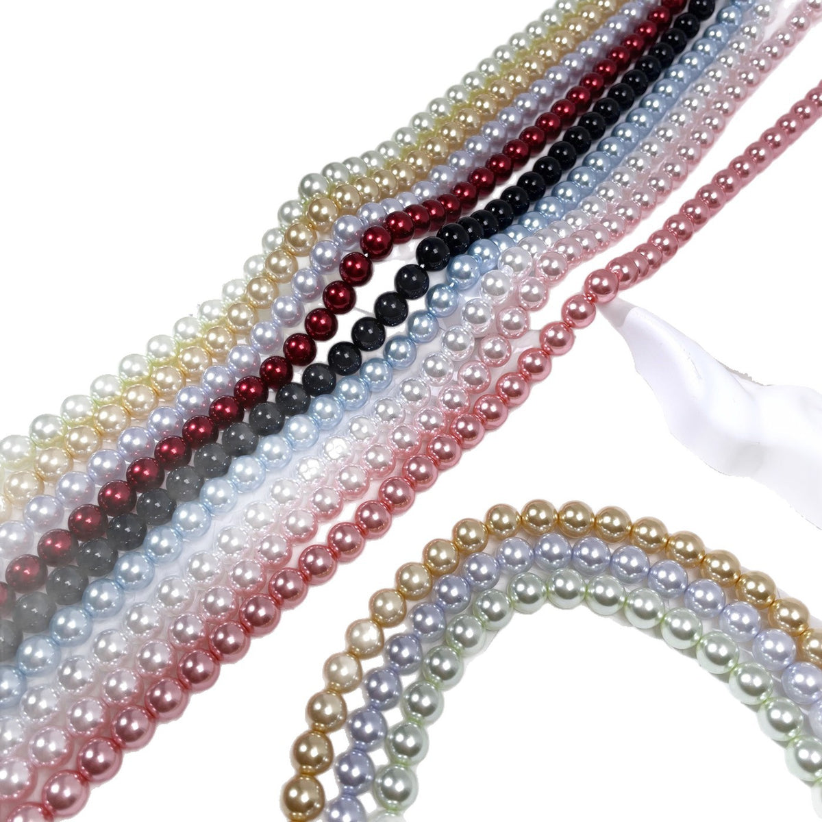 Diagonal rows of glass pearl bead strands in gold, red, black, blue, pink, and cream on white