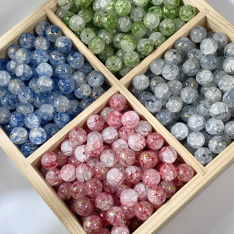 Wooden tray with blue, green, gray, and pink crackle glass beads with gold-silk details