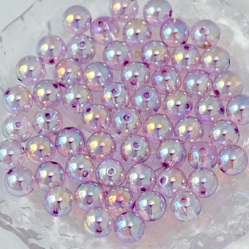 A pile of round iridescent beads with a lavender-purple base color and rainbow reflections, resting on a clear textured surface.