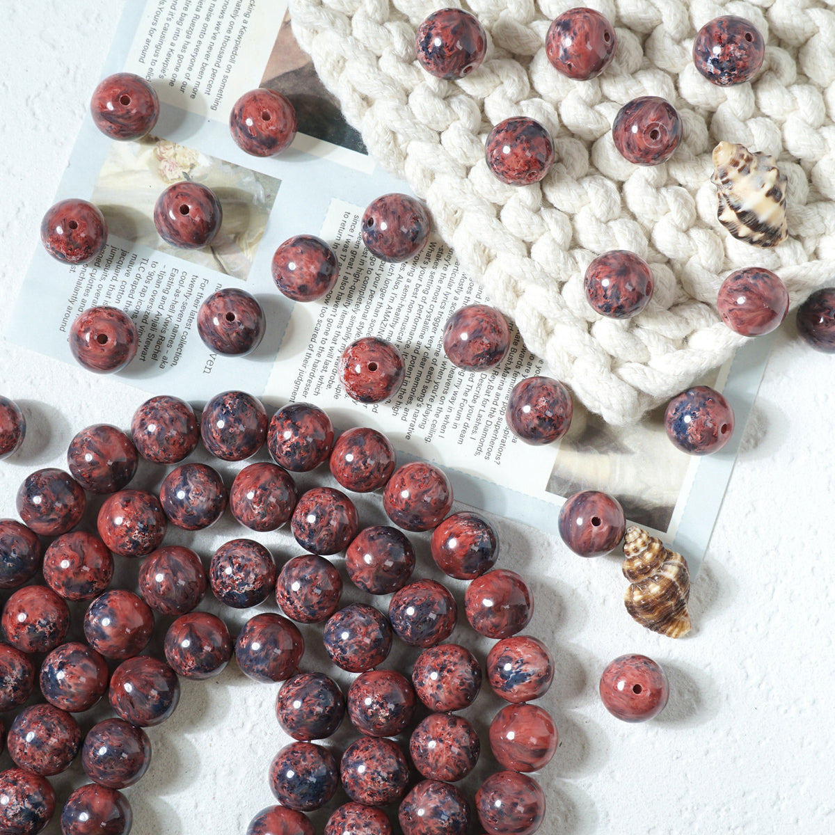 Red and black marbled round glass beads scattered on a white surface