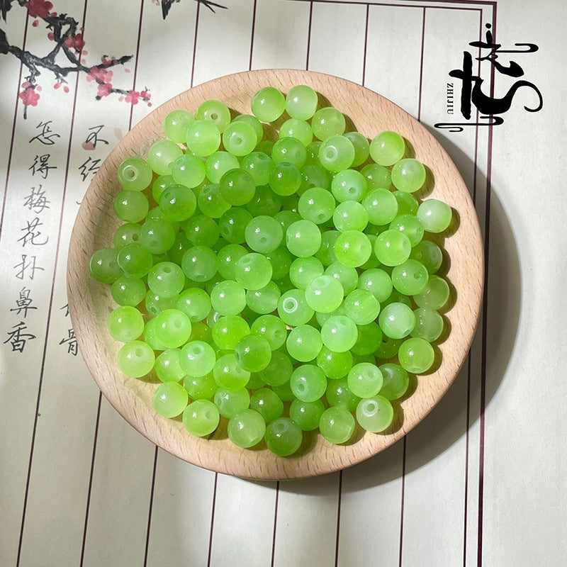 Bright green translucent round beads in a wooden bowl with calligraphy