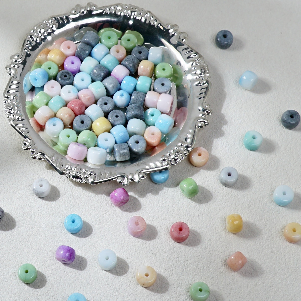 Pastel-colored round craft beads with center holes in ornate silver bowl