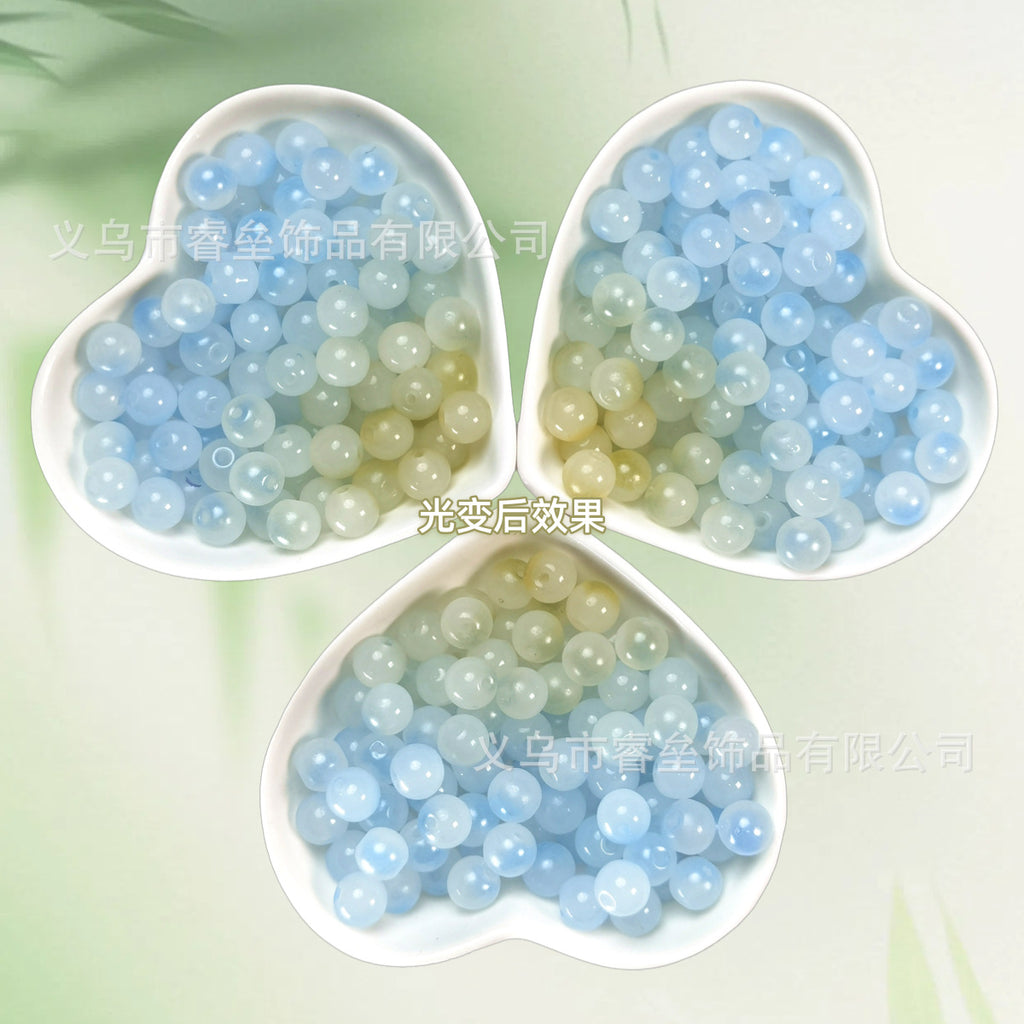 Three heart-shaped bowls of pale blue and soft green translucent beads on light green