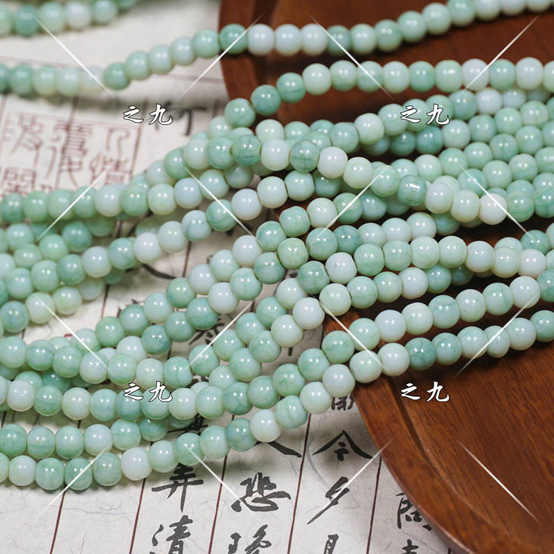 Green jadeite round porcelain bead strands with glossy finish on wooden tray