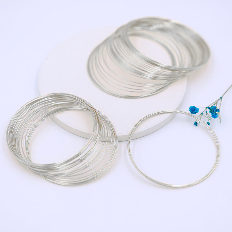 Silver-colored memory wire bracelet rings, coiled stacks with one ring flat, blue flower sprig