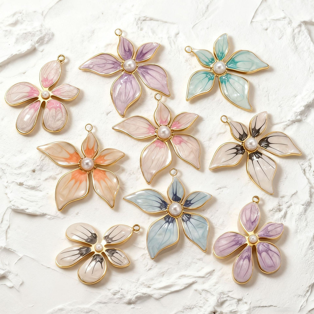 Nine gold-toned enamel flower pendant charms with pearl centers in pink, purple, teal, orange, and blue on white