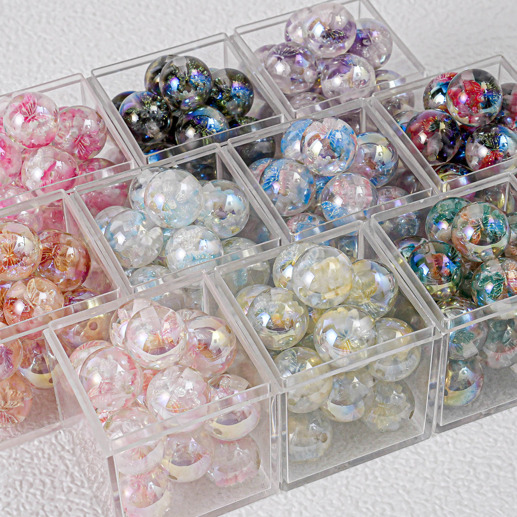 Colorful round butterfly beads in clear plastic compartment boxes on white