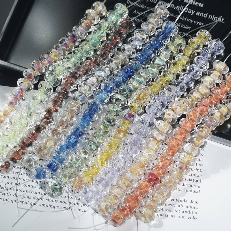 Strands of water-ripple lampwork glass beads in blue, yellow, orange, pink, purple and green on printed book pages