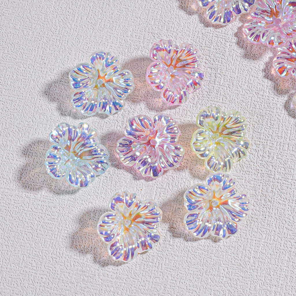 Iridescent resin flower beads in pastel pink, blue, purple and yellow on a textured white surface