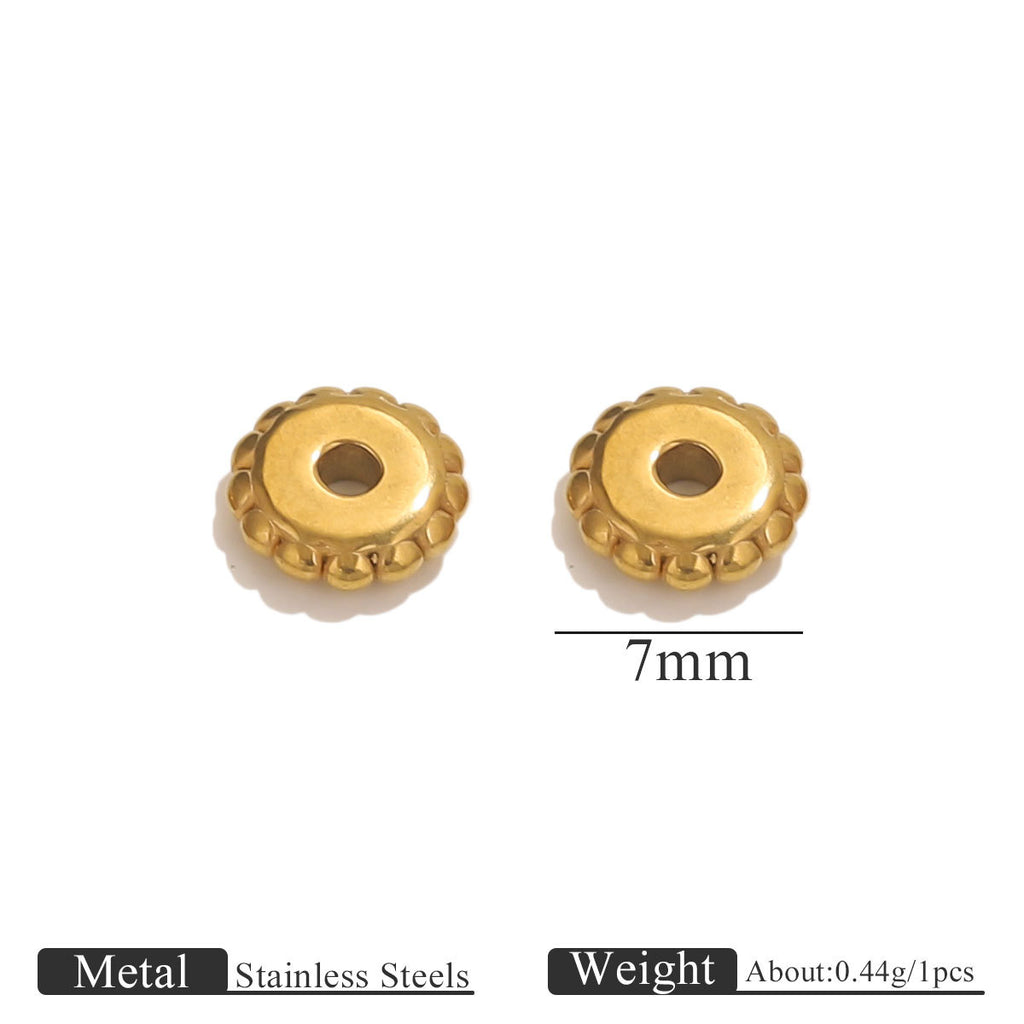 Two small gold-plated dotted gear wheel stainless steel spacer beads with scalloped edges and central holes on white