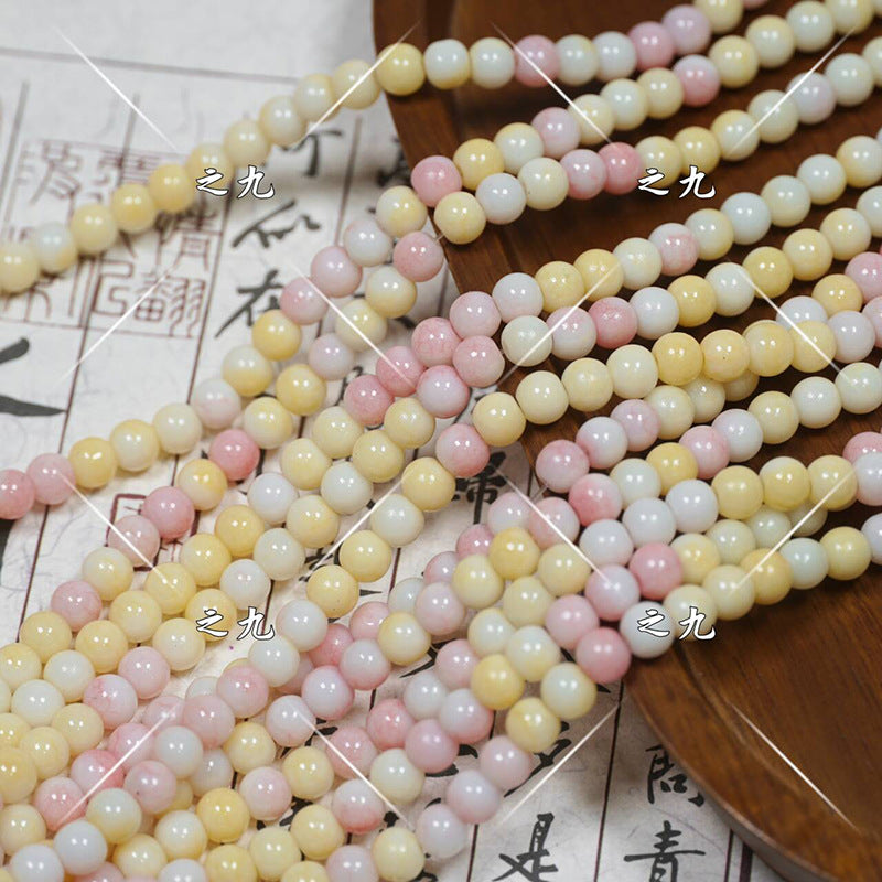 Multicolor pastel porcelain bead strands in pink, yellow, white on wooden tray