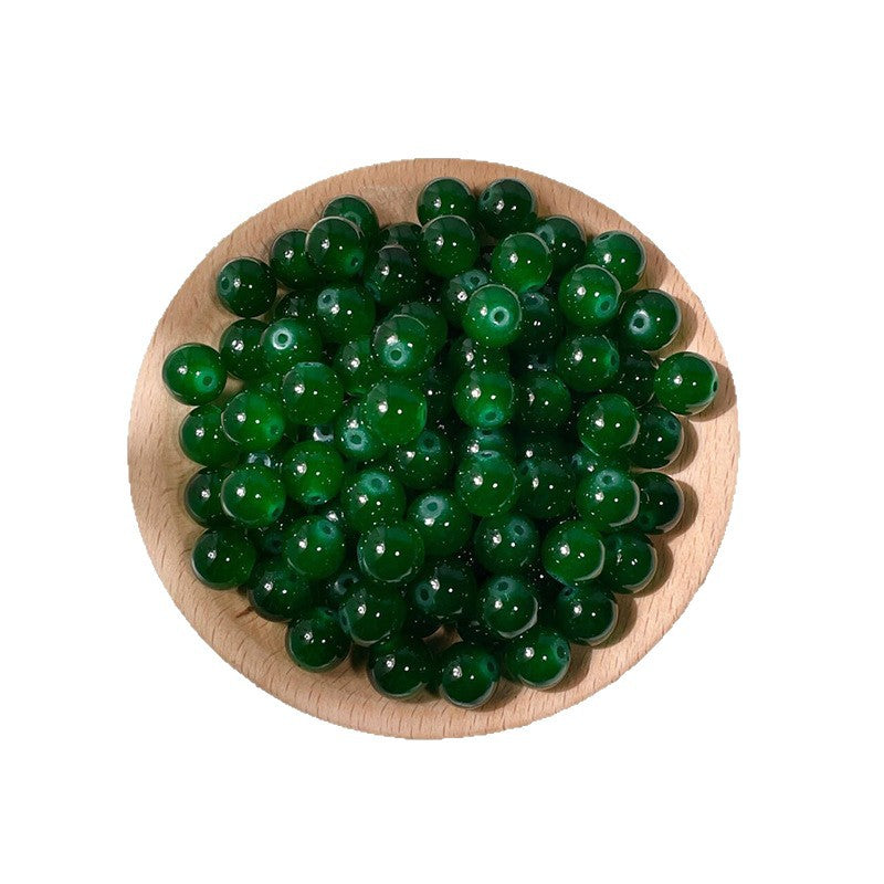 Green round glass beads in a wooden bowl on white background