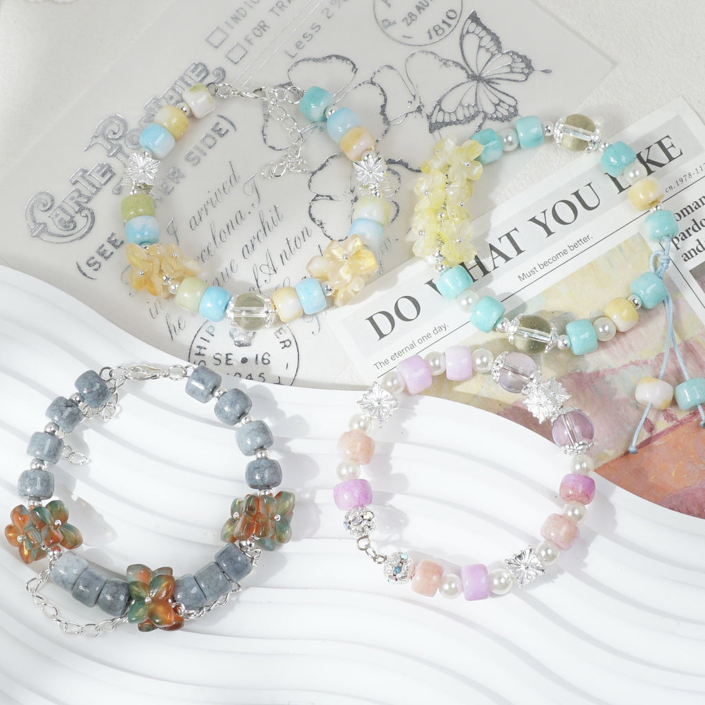Three beaded stretch bracelets on white textured surface with vintage printed paper
