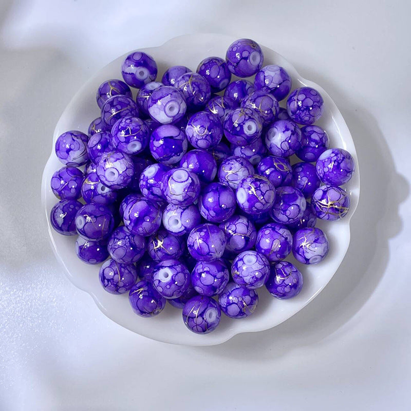 White bowl of marbled bright purple glass beads with gold-silk veining