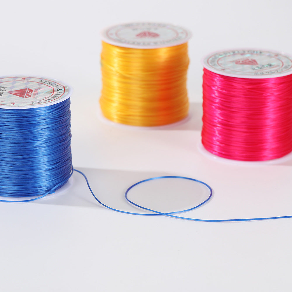 Blue, yellow and pink spools of flat elastic beading cord with a loose blue strand looping across a white surface