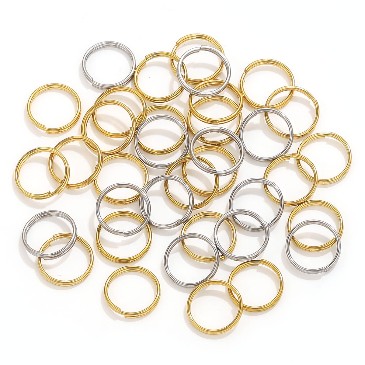 Gold and silver mini split ring connectors piled on white background