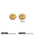 Two small gold-plated dotted gear wheel stainless steel spacer beads with scalloped edges on white
