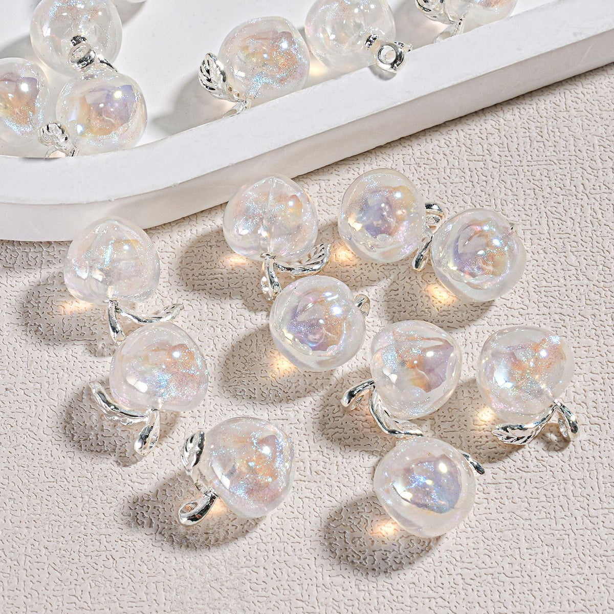 Clear pear-shaped iridescent mini peach beads with holographic finish on silver loops