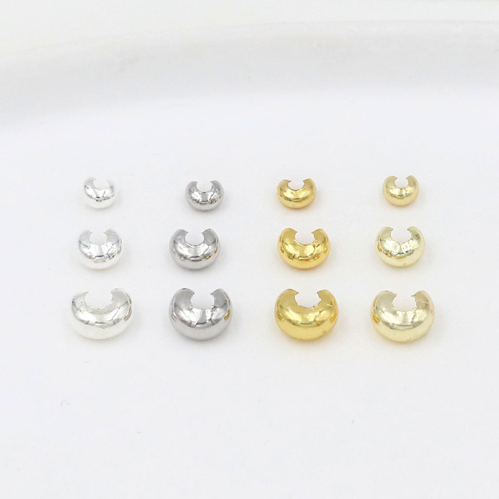 Twelve C-shaped crimp bead covers in three sizes and silver and gold finishes arranged in three rows on white