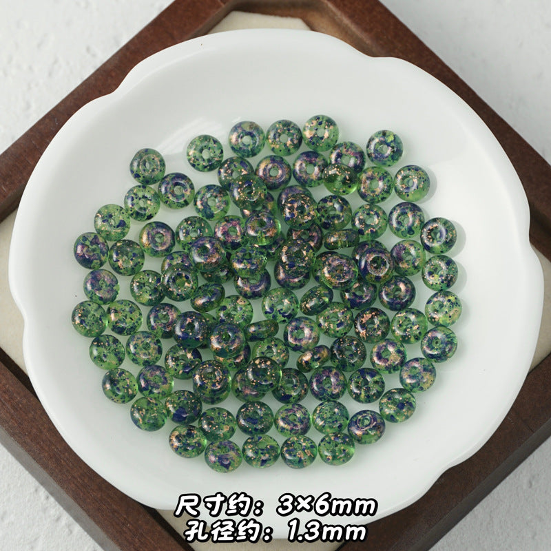Green iridescent Picasso-finish glass abacus beads with glittery finish in a white scalloped dish on wooden tray.