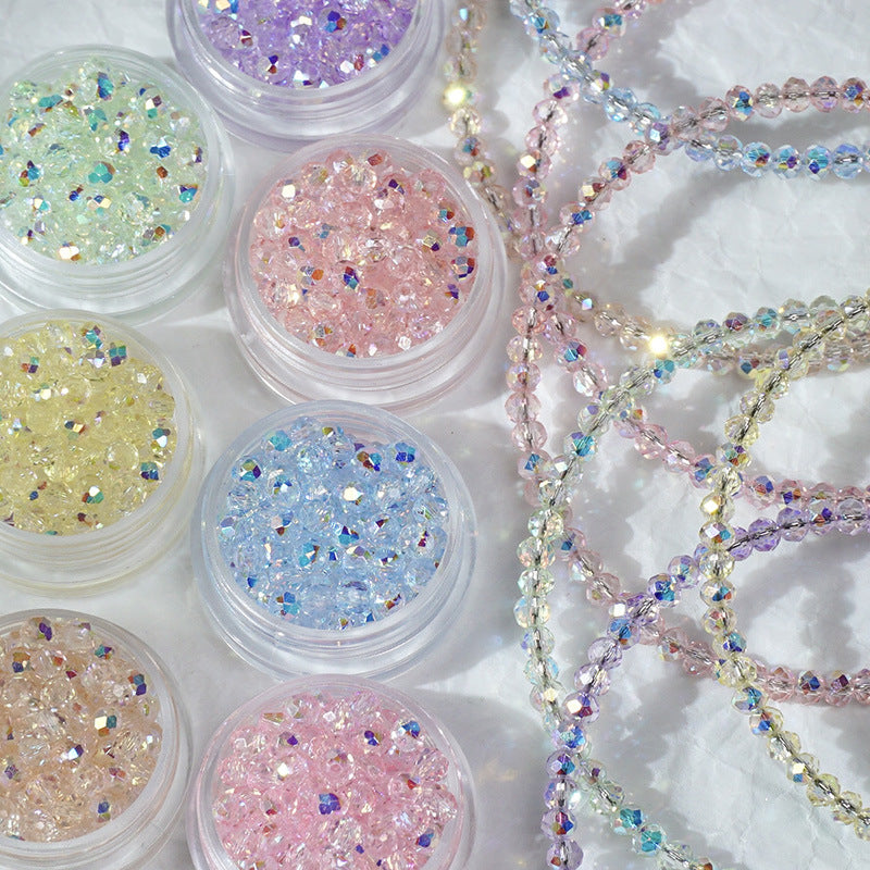 Six small clear jars filled with iridescent rhinestones in pastel shades, arranged beside strands of matching beaded chains on a white textured background.