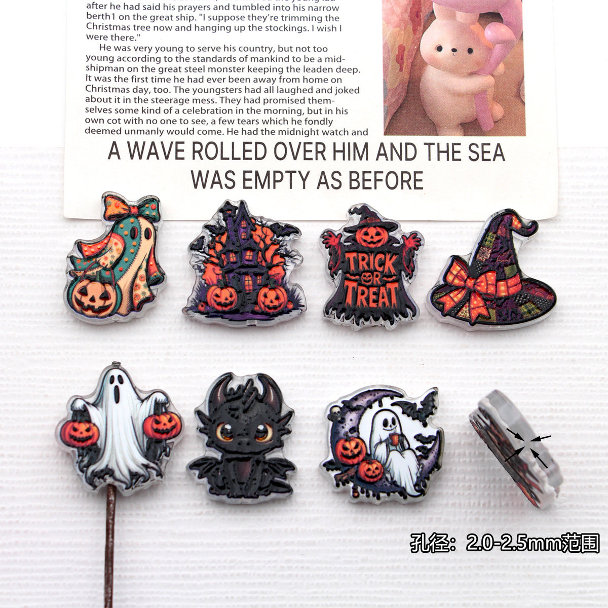 Seven Halloween acrylic beads with witch, ghost, pumpkin, haunted house, and bat designs on white
