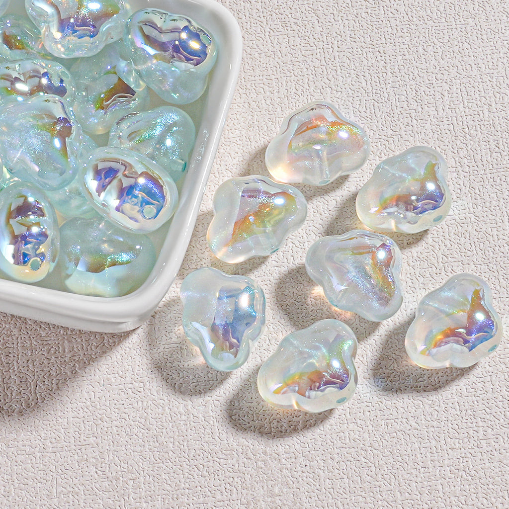 Milky white cloud-shaped resin beads with rainbow iridescence in a white tray and on beige surface