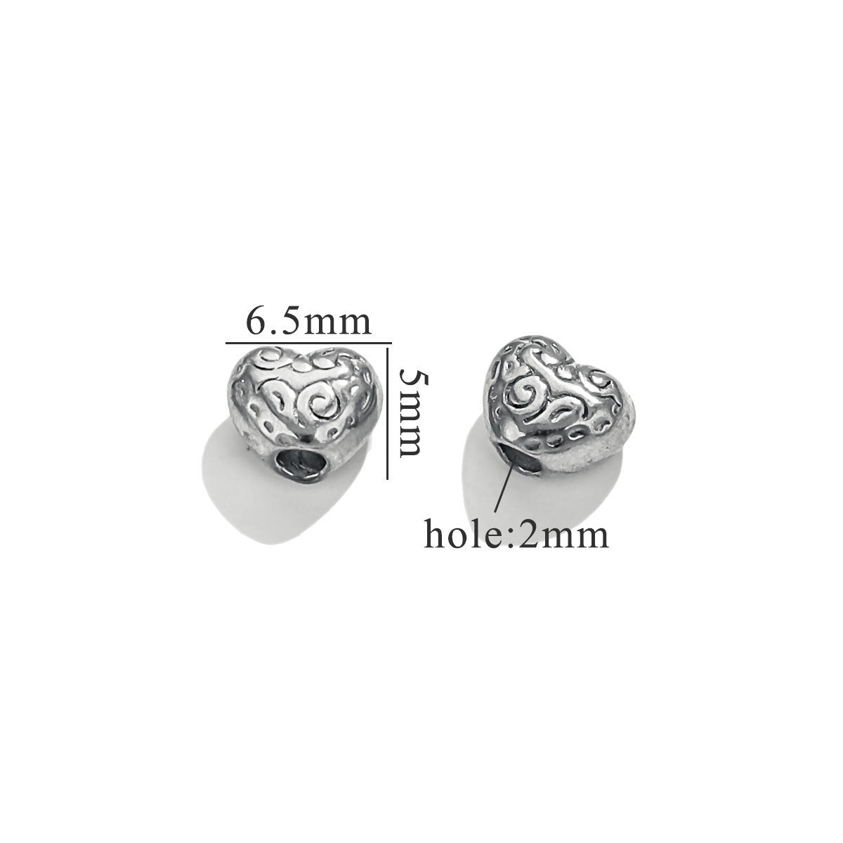 Two steel-color heart-shaped baroque bead charms with engraved swirl patterns on white background