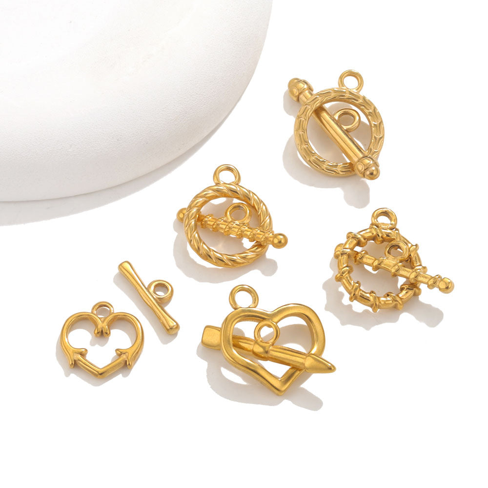 Six gold-tone toggle clasp charms, heart and rope circular designs, on white background with curved prop