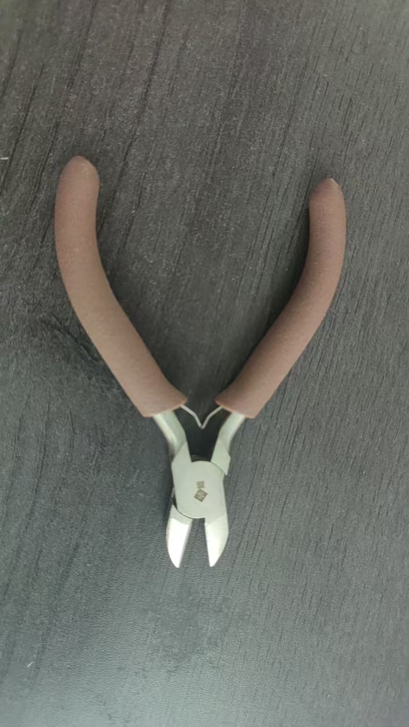 Brown-handled wire nippers with silver blades on dark gray