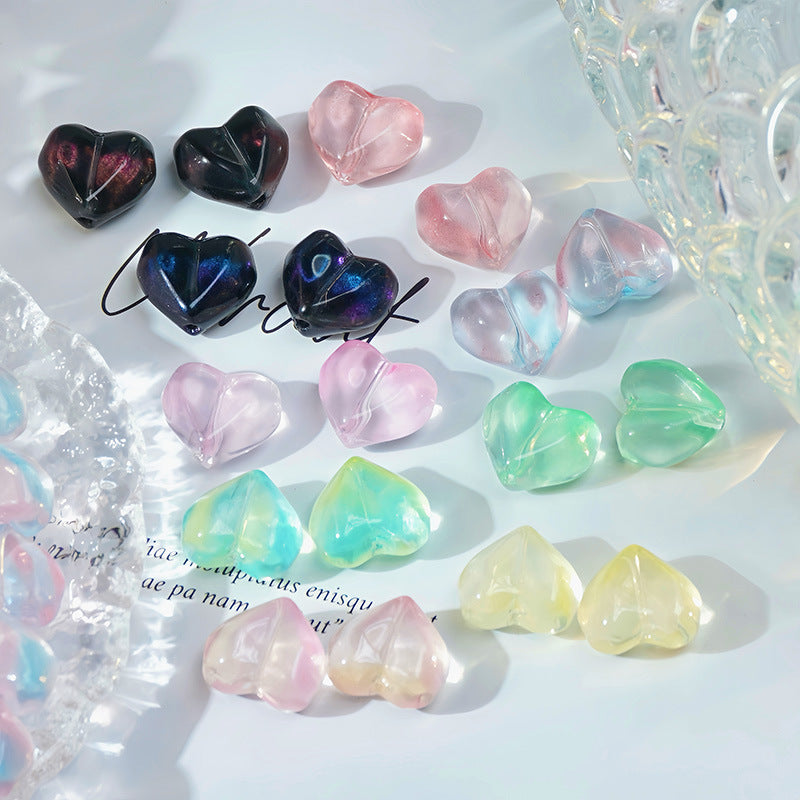 Heart-shaped translucent faceted glass beads in blue, pink, green, yellow and clear on a white surface