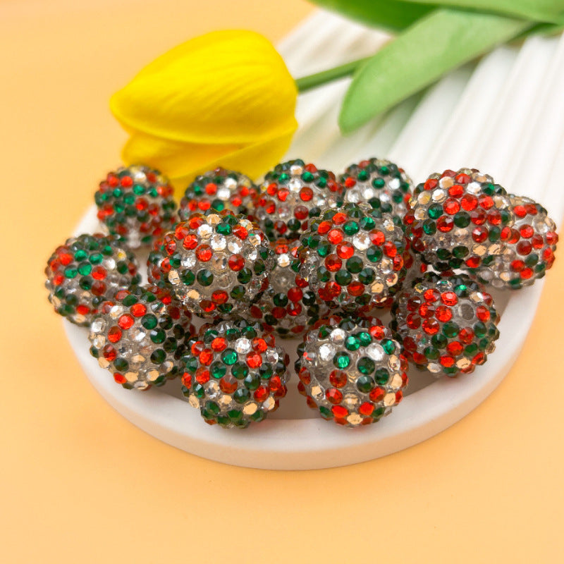 Round red, green and clear rhinestone beads on a white dish with yellow tulip