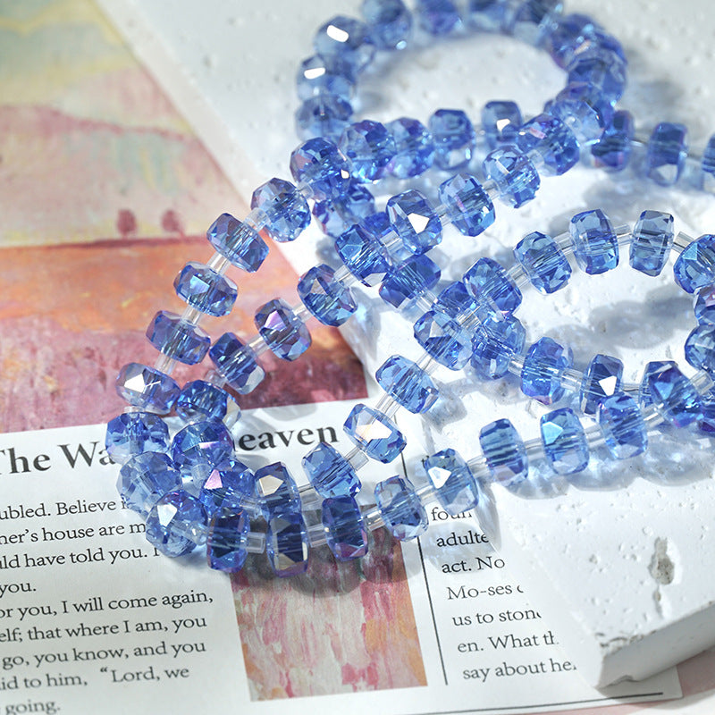 Blue faceted glass beads strung on elastic bands, arranged on top of an open book page.