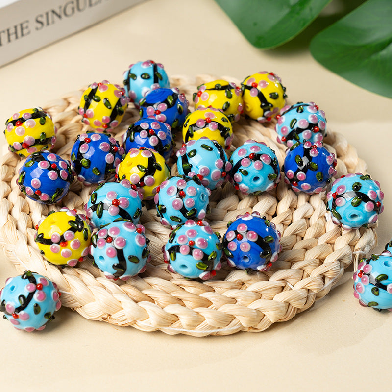Pile of colorful perforated glass round pendant beads with floral patterns