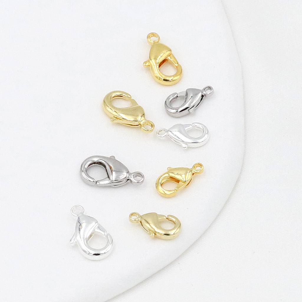 Eight gold and silver teardrop lobster clasps arranged on a white background
