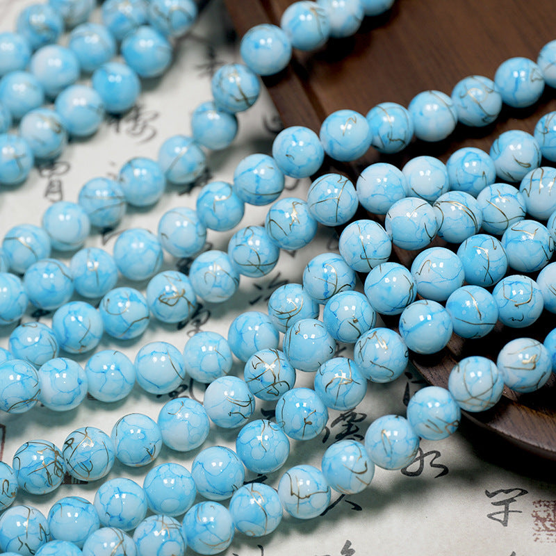 Light blue marbled porcelain bead strands with gold veins on paper