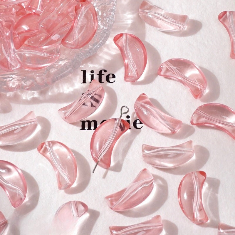 Pink translucent crescent glass beads on white with a bowl and a metal pin