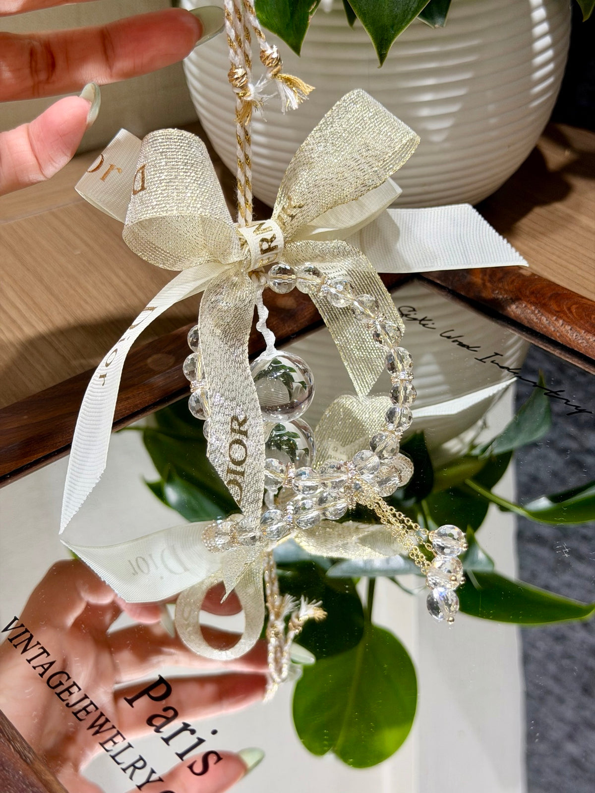 White crystal car hanging ornament with woven gold bow and crystal tassel reflected in mirror